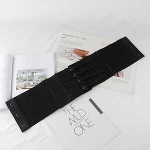 Vue à plat de la ceinture corset noire avec boucles métalliques sur des magazines
