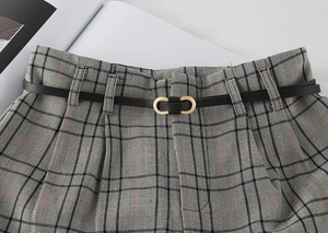 Close-up of black thin waist belt with golden double ring buckle on plaid fabric