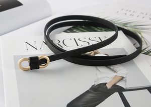 Detailed view of women black slim belt with gold interlocking oval metal buckle