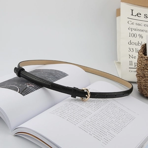 Chic black slim leather belt for women featuring a round golden buckle on a magazine