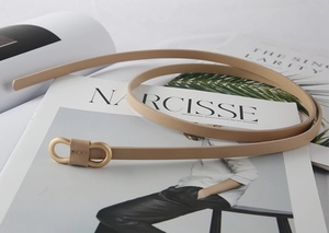 Detail of nude leather skinny belt with elegant matte gold double ring buckle design