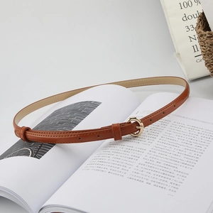 Close-up of a minimalist caramel brown leather belt with a polished gold round buckle