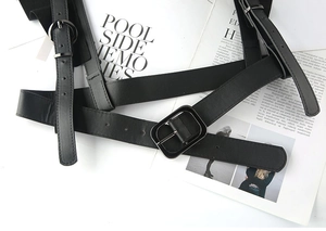 Detail of black PU leather punk harness with silver metal buckles and adjustable eyelets