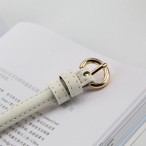 Close-up of a white slim leather belt with a polished gold round buckle and stitching