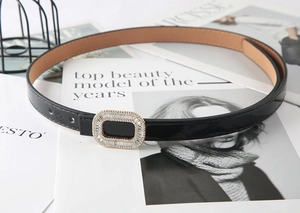 Close-up of elegant black skinny belt with luxury rhinestone buckle on fashion magazine