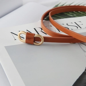 Chic caramel brown slim leather belt with gold double-ring buckle on fashion magazine