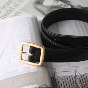 Minimalist black belt with golden square buckle on a fashion magazine background