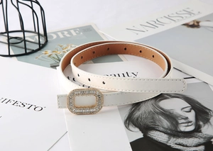 Detail of white skinny belt for women featuring a gold buckle with crystal rhinestones