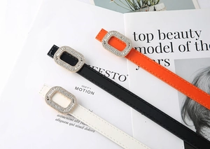 Detail of slim waist belts with sparkling rhinestone square buckles in white, black and orange