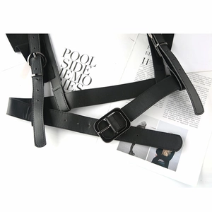 Flat lay of a black punk-style PU leather waist belt with multiple buckle straps on a magazine