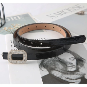 Elegant black patent leather belt for women with sparkling rhinestone buckle on magazines