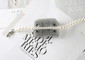 Mini sac accessoire en strass avec chaîne de perles blanches posé sur un magazine épuré