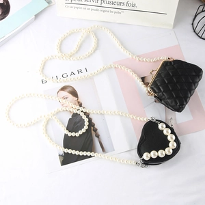 Close-up of heart-shaped mini bag with pearls and vintage quilted pouch with chain