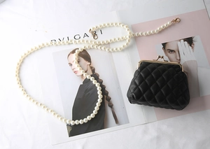 Detail of black quilted mini pouch with pearl chain strap and vintage gold metal clasp