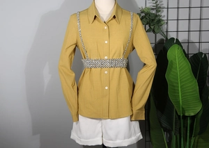Close-up of a silver rhinestone body chain harness styled over a yellow shirt