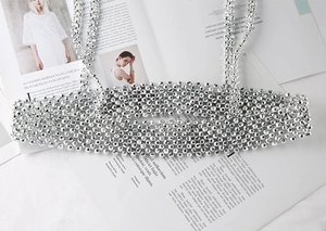 Detail of silver beaded body chain harness featuring a metallic woven pattern texture