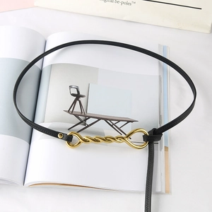 Detail of thin black leather belt with elegant golden twisted buckle on a lifestyle setup