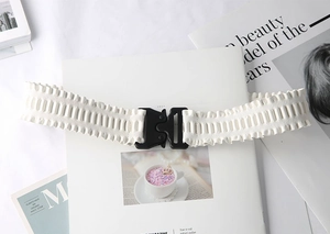 Detail of white ruffled elastic waist belt with black matte plastic buckle on magazine