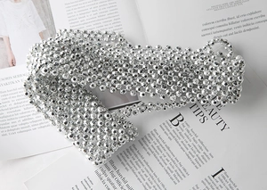 Detail view of woven silver faceted bead belt with metallic shine on a magazine