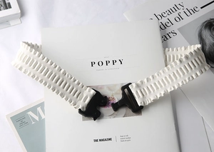 Macro shot of the white pleated elastic fabric and black plastic buckle detail