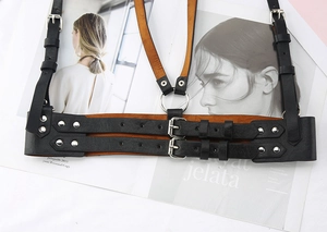 Detail of punk style black leather body harness with silver buckles and metal rings
