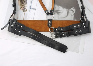 Detailed close-up of punk style PU leather body harness with silver metal rings and buckles