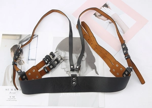 Detail of black leather punk harness with metal rings and adjustable buckles on magazines