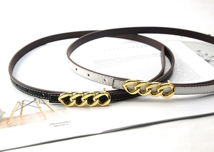 Detail view of thin leather belts with gold chain buckles in black and light grey colors