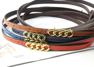 Detail view of thin Saffiano leather belts featuring elegant gold triple-chain link buckles