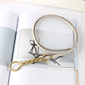Close-up of beige leather belt with herringbone stitching and golden double-ring buckle