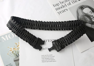 Detail of black elastic wide waist belt with a matte plastic buckle and pleated texture