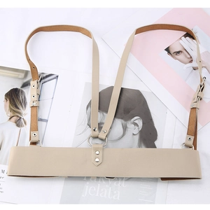 Close-up of beige leather harness belt with silver O-rings and adjustable straps