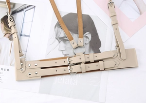 Detail of beige PU leather body harness with silver metal rings and adjustable straps