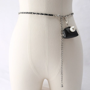 Detail of silver chain belt with small black pouch and decorative white pearl button