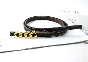Detail of slim dark brown leather belt with white stitching and gold chain buckle design