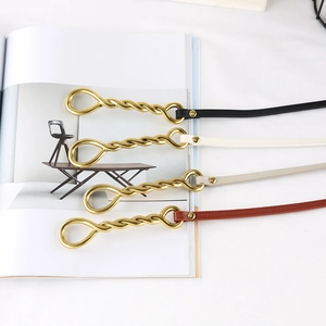 Close-up of thin leather belts in four colors with twisted gold metal buckles on a magazine