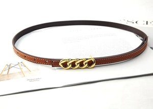Detail of slim brown leather belt with gold chain buckle and white contrast stitching
