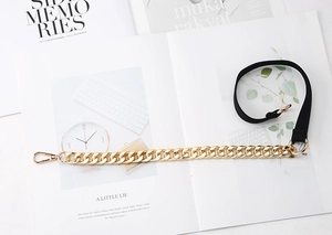 Detail of fashion waist belt featuring gold metal chain and black elastic band texture