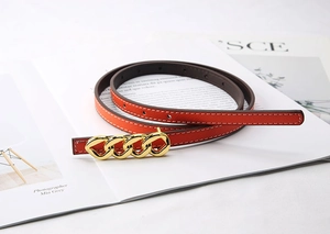 Detail of orange Saffiano leather belt with golden four-link chain metal buckle