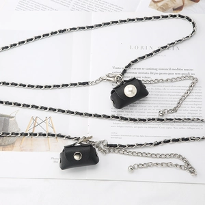 Mini leather belt bag with silver metal chain and pearl clasp on fashion magazine background