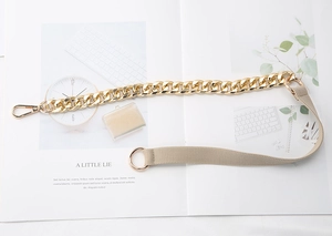 Detail of the golden metal chain and beige fabric strap with lobster clasp