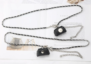 Detail of black mini leather pouches with pearl accents and silver metal chain straps