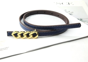 Detail of navy blue cross-grain leather belt featuring a golden triple ring chain buckle