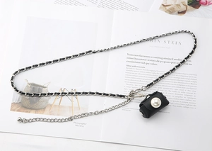 Detail of woven leather metal chain belt featuring a mini pouch with large white pearl