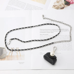 Detail showing mini black leather bag with pearl closure and silver chain waist belt