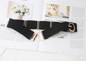 Detail of wide elastic belt with gold G-shaped buckle and metallic square accents