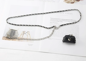 Detail of silver metal waist chain with black leather and mini pouch on a magazine