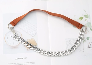 Detail view of silver metal chain joined with brown nylon webbing and lobster clasps