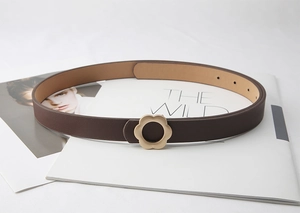 Détail d'une fine ceinture en cuir marron avec boucle élégante en forme de fleur dorée