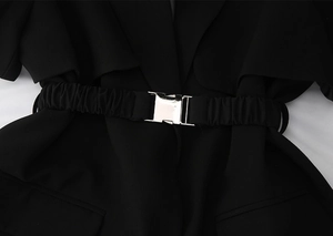 Détail de la boucle en métal argenté sur une ceinture noire élastique à plis